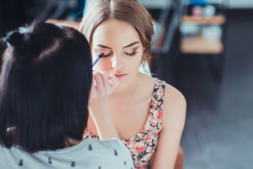 esthetician doing makeup on beautiful young woman