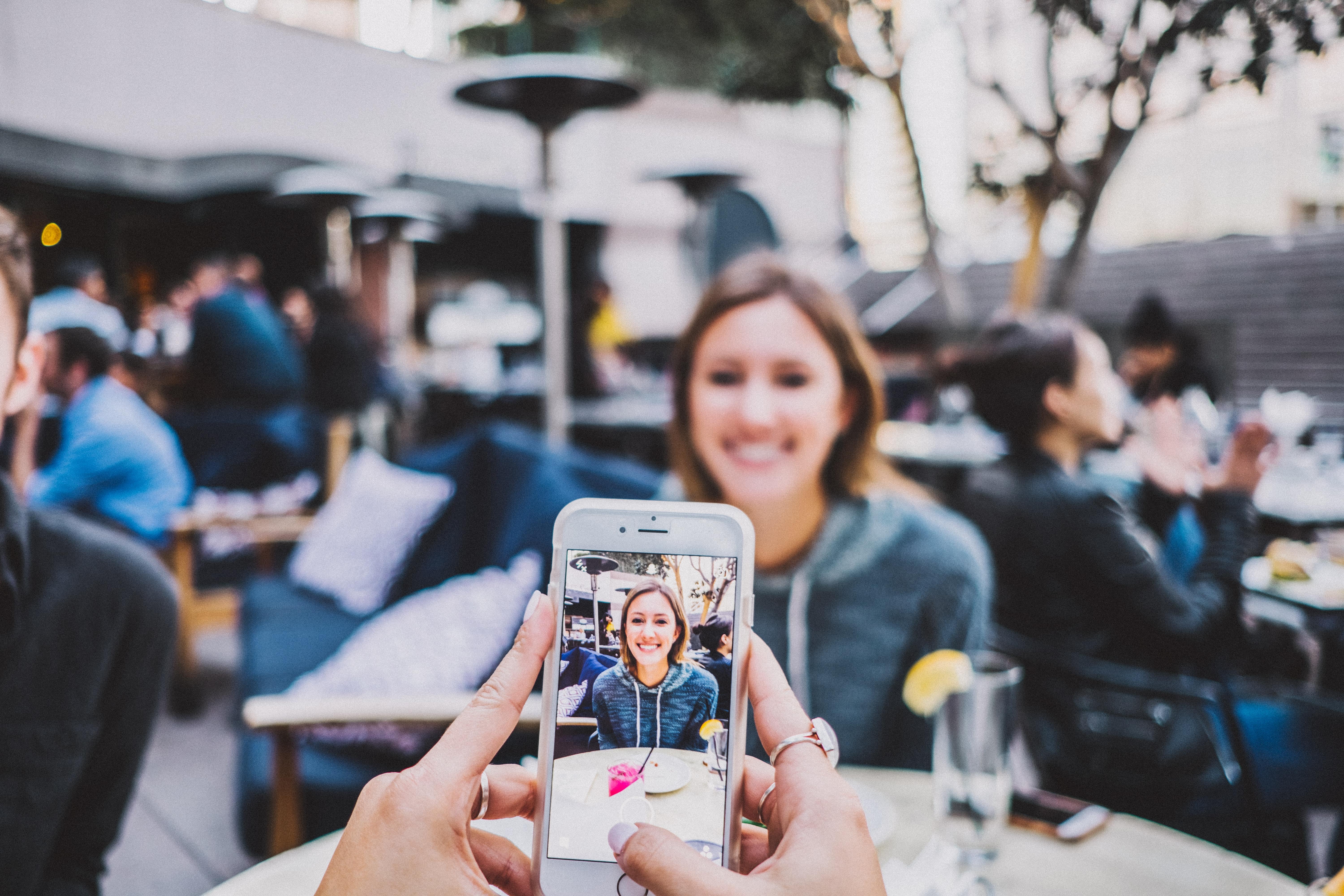 someone taking photo of woman on iPhone
